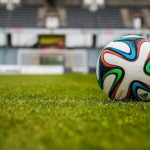 Vibrant soccer ball on a lush green field in an empty stadium.